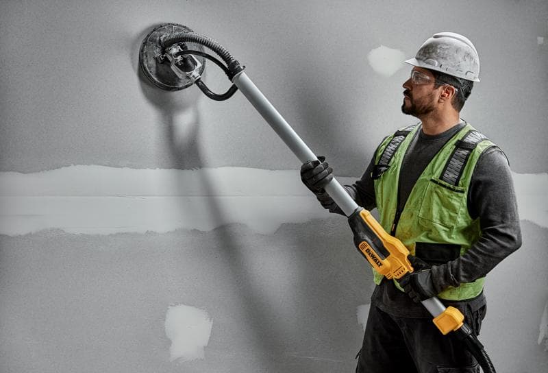 Trabajador usa DEWALT DWE7800, DWE7800-QS lijadora en pared de yeso. Producto de fotografía.