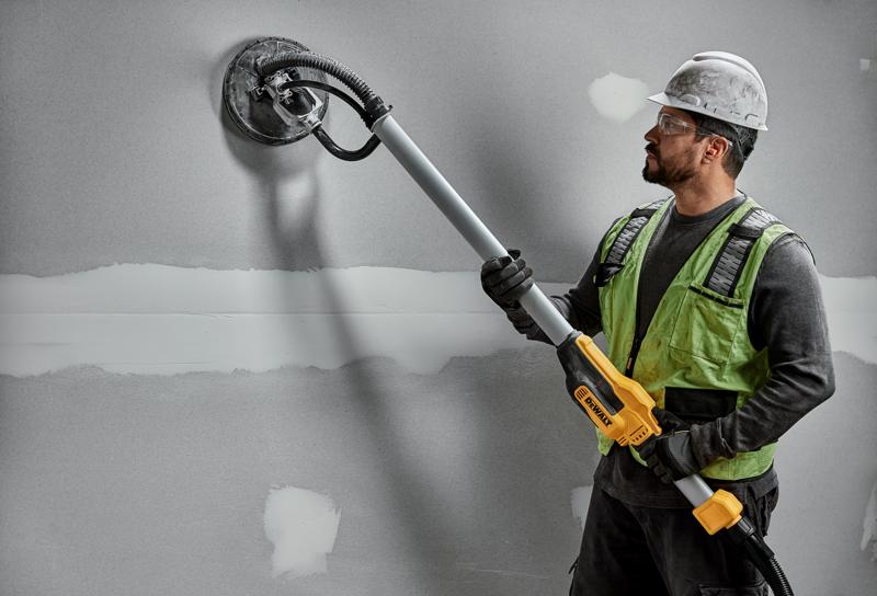 Trabajador usa DEWALT DWE7800, DWE7800-QS lijadora en pared de yeso. Producto de fotografía.